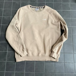 Beige sweatshirt från ICANIWILL - Säljer en stilren beige sweatshirt från ICANIWILL med diskret logga på bröstet. Tröjan har rund halsringning, långa ärmar och ribbade muddar. 