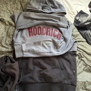 Grå HOODRICH tracksuit med röd logga - Snygg grå tracksuit från HOODRICH med stor röd och svart logga på bröstet ich en röd svart logga vid låret på byxorna.