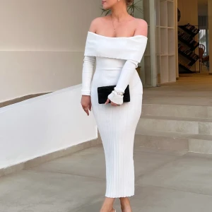Vit ribbad offshoulder långklänning - Säljer en elegant vit långklänning med ribbad struktur och offshoulder-design. Klänningen har långa ärmar och figurnära passform som framhäver siluetten. Perfekt för dig som gillar stilrena och trendiga looks. 