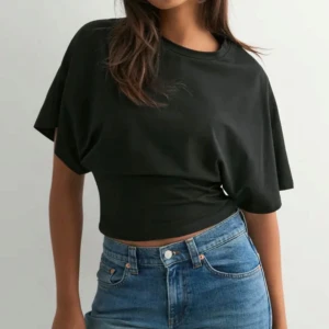 Svart croppad topp med loose fit - Snygg svart croppad topp med loose passform och korta ärmar. Toppen har en enkel, stilren design med rund hals och är tillverkad i mjuk bomull. Säljer då den inte kommer till användning 💕
