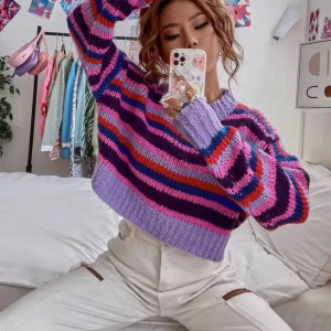 Randig croppad stickad tröja - Superfin croppad stickad tröja med breda ränder i lila, rosa, röd, blå och mörklila. Tröjan har lång ärm, ribbade muddar och en relaxed fit. Perfekt för dig som gillar färg och vill sticka ut lite extra.