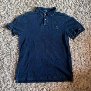 Ralph Lauren piké slim fit - Säljer denna riktigt snygga marinblå Ralph Lauren piké i storlek L, slim fit. Den är i bra skick utan defekter. Bara att skriva över frågor och funderingar.