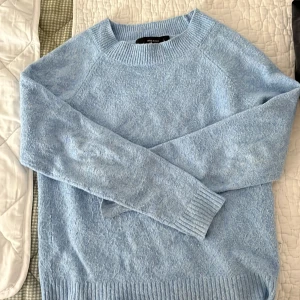 Ljusblå stickad tröja från Vero Moda - Mysig ljusblå stickad tröja från Vero Moda med rund halsringning och ribbade muddar vid ärmslut och nederkant. 