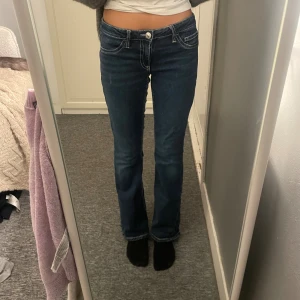 Blå bootcut jeans Gina Tricot Young - Snygga mörkblå bootcut jeans från Gina Tricot Young med kontrastsömmar och coola bakfickor med knapp och broderad detalj. Klassisk femficksmodell och låg midja. Perfekta för dig som gillar en retro vibe och vill ha ett par jeans som sticker ut. Ser inte så snygga ut när de hänger på galgen men på ser de bättre ut!😂💙✨