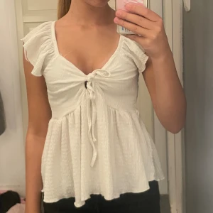 Vit blus från 157🤍✨ - Supersöt vit blus från 157 i storlek XS. Toppen har volangärmar, v-ringning och snygg snörning framtill som ger en feminin touch. Materialet är lätt och krusat, vilket gör den extra luftig och skön. Perfekt att styla med jeans eller kjol för en chill look.👀✨🤍