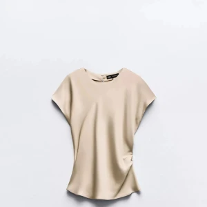 Beige blus från Zara i sidenlook - Supersnygg beige blus från Zara med rund hals och korta ärmar. Aldrig används 