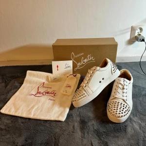 Christian Louboutin vita sneakers med nitar - Säljer nu mina super snygga Christian louboutins sneakers i storlek 39, skorna är i helt nytt skick fick de i födelsedagspresent men säljer då jag har flera skor, skorna har tre tillbehörande extra nitar till, skriv gärna om ni är intresserade 🥰❤️