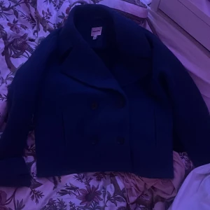 Mörkblå skepparkavaj från Kappahl XS den sitter som S och jätte fin fråga om flera bilder om de e så! - Säljer en mörkblå skepparkavaj från Kappahl i storlek XS. Jackan har dubbelknäppning framtill, bred krage och knappar vid ärmsluten. Klassisk och stilren modell som är enkel att matcha till olika outfits. Original pris 800-900kr