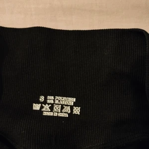 Svarta träningsshorts från DFYNE - Svarta träningsshorts från DFYNE med hög midja och ribbad linning. Tillverkade i stretchigt material med 90% polyamid och 10% elastan, vilket gör dem perfekta för träning. Snygg logga på linningen och tight passform som framhäver formen.