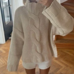 Helt ny beige stickad tröja - Slutsåld beige stickad tröja från zara med grovt kabelmönster framtill och hög krage. Tröjan har en loose passform och långa ärmar med breda muddar. (De två första bilderna är lånade)