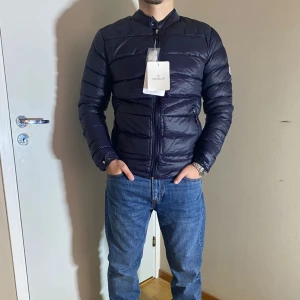 Moncler Jacka - Snygg vindjacka från Moncler med quiltad design och dragkedja framtill. Jackan har långa ärmar och en rund halsringning. Perfekt för vindiga dagar med sin stilrena look och varma material. Finns olika storlekar och passa på nu när hösten börjar 😊🍁