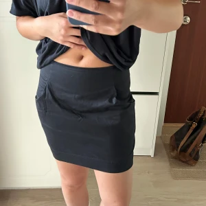 Svart kortkjol från Samsøe Samsøe - Svart kortkjol från Samsøe Samsøe i modellen Nuka skirt. Kjolen har en tight passform, diskreta fickor på sidorna och dragkedja bak. Aldrig använt och nyskick 