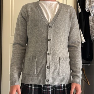 Grå cardigan från John Henric, M - Säljer en stilren grå kofta från John Henric i storlek M. Koftan har v-ringning, knäppning framtill med fem knappar och två praktiska fickor. Tillverkad i mjukt material som passar perfekt till lager-på-lager. Ribbstickade muddar vid ärmslut och nederkant.        Nypris 1500                                               Använd ett fåtal gånger