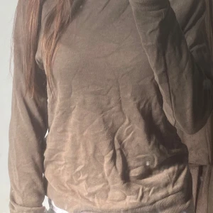 Beige långärmad tröja från Athlecia - En basic beige långärmad tröja från Athlecia. Tröjan har rund halsringning, ribbade muddar och är tillverkad i mjukt bomullsmaterial. Perfekt för en chill och avslappnad stil. Passformen är normal och färgen är lätt att matcha med det mesta.