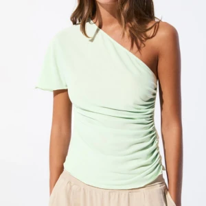 Ljusgrön oneshoulder topp - Snygg ljusgrön topp med oneshoulder-design och lätt rynkade detaljer längs sidan. Strl s endast testad!🥰🥰