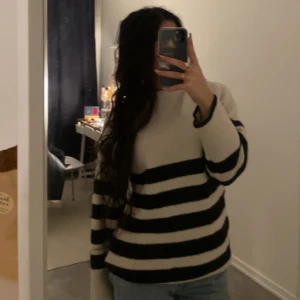 Randig stickad tröja - Säljer en mysig stickad tröja med svartvita ränder. Tröjan är väldigt lång men går o vika in botten på den för att få looken i första bilen elle ha kvar den för en mysig vibe. Perfekt för kyligare dagar och ger en stilren look. Passar bra till jeans eller tights