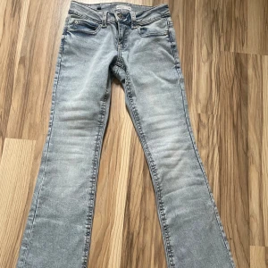Ljusblå bootcut jeans - Snygga ljusblå bootcut jeans med klassisk femficksdesign och knappar bak. Perfekta för en avslappnad stil. De har en lätt tvättad look och är tillverkade i ett bekvämt denimtyg. Har en snöra innanför jeansen i midjan för att dom inte passade i midjan för mig men dom var lite korta i benen enligt mig och dom är typ sprillans nya så därav säljs dom för ny pris. Endast använts en gång.