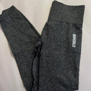 Grå mjukisbyxor från Gymshark - Säljer ett par grå mjukisbyxor från Gymshark. De har en hög midja och en bekväm passform med snörning i midjan. Perfekta för en avslappnad stil eller träning.