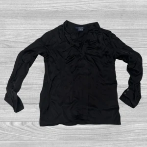 Svart blus från Gant - Elegant svart blus från Gant med långa ärmar och en stilren design. Perfekt för en chic look. Blusen har en diskret v-ringning och knappar vid ärmsluten.