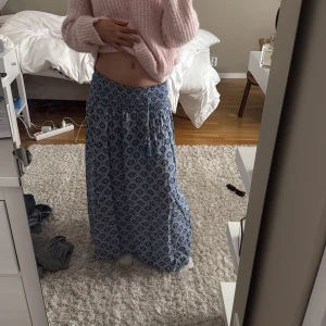 Blå långkjol med mönster - Snygg blå långkjol med ett unikt mönster. Kjolen har en lös passform och är gjord i ett lätt material som passar bra till varmare dagar. Fina färger 