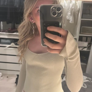 Beige ribbad tröja från Gina Tricot - Säljer en stilren beige ribbad tröja från Gina Tricot. Tröjan har en unik v-ringad design och långa ärmar, perfekt för en trendig look. Passar bra till både jeans och kjol. Perfekt för höst och vår! Den har ett litet hål i armhålan 