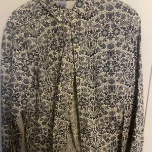 Mönstrad skjorta från Tailored Originals - Snygg långärmad skjorta från Tailored Originals med ett detaljerat blommönster i svart och beige. Skjortan har en slim fit passform och är perfekt för att ge en stilren look.