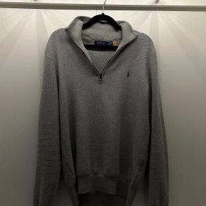 Ralph Lauren half zip - Säljer en stilren grå half zip från Polo Ralph Lauren. Tröjan har använts endast en gång, detta är för att den är för liten för mig. Den är i 10/10 skick, hör av dig!