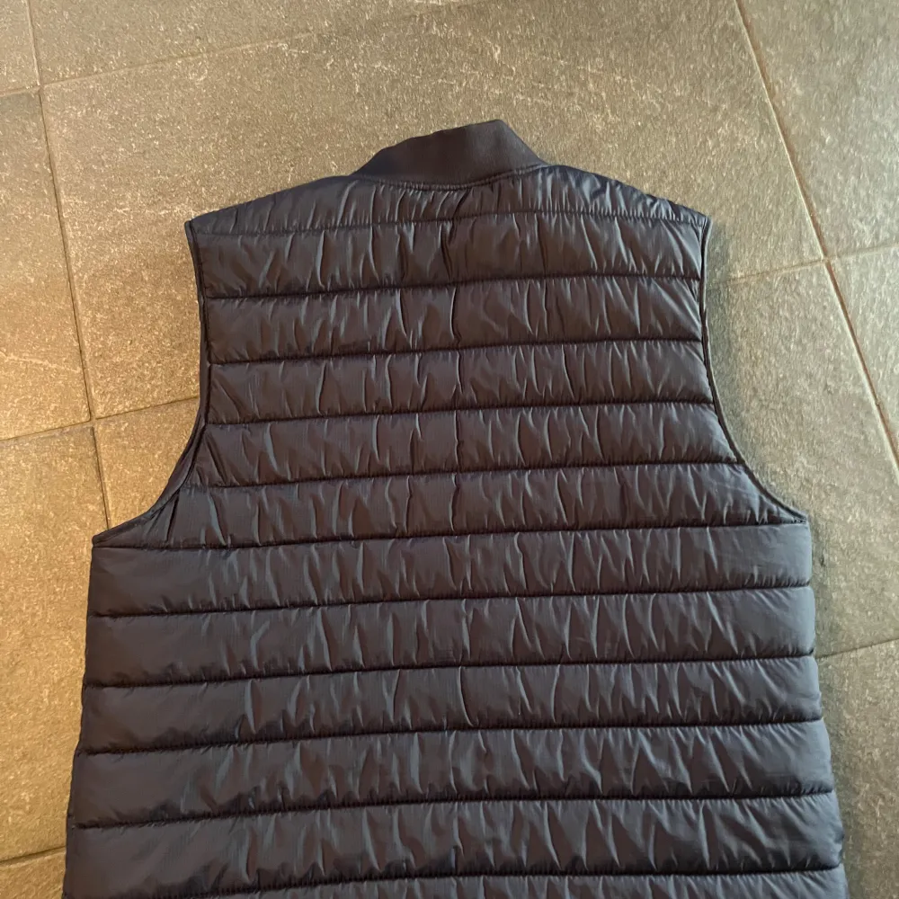Snygg svart quiltad väst från Zara med dragkedja framtill. Perfekt för lager-på-lager under kyligare dagar. Västen har en stilren design med två fickor på sidorna.. Takit.