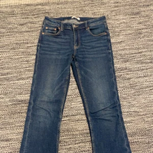Blå jeans från Gina Tricot - Snygga blå jeans från Gina Tricot med klassisk femficksdesign och knappgylf. Perfekta för en avslappnad stil med en touch av vintagekänsla. Passar bra till både sneakers och boots.