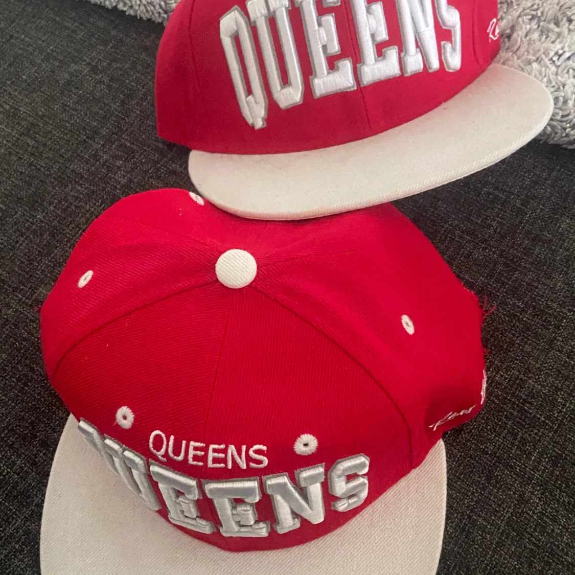 Röd keps med texten 'QUEENS'