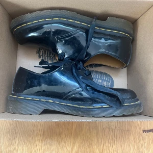 Svarta ”loafers” från Dr. Martens - Snygga svarta loafers från Dr. Martens med klassisk design och robust sula. Skorna har snörning och den ikoniska gula sömmen runt sulan. Perfekta för en stilren look. Skorna är i bra skick och jag har redan gått in i dom vilket gör att dom inte gör ont att i gå i💕priset kan diskuteras🥰