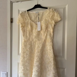 Vit klänning från Ida Sjöstedt - Helt ny klänning från Ida Sjöstedt. Lapparna är kvar. Millie dress rosé storlek 40 färg Ivory. Köpte den till min student men valde en annan tillslut. Otroligt fin klänning. Perfekt till studenten. Eller varför inte till bröllopsfesten! Säljer en vacker vit klänning från Ida Sjöstedt med korta ärmar och ett blommigt mönster. Klänningen har en elegant design med en fin struktur av små blommor över hela tyget. Perfekt för speciella tillfällen!