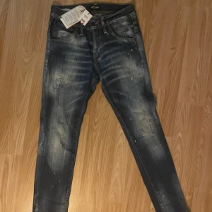 Blå jeans från Jack & Jones - Snygga blå jeans från Jack & Jones med en cool tvättad look och slitna detaljer. Designade och tvättade i Italien. Perfekta för en avslappnad stil med en touch av edge.