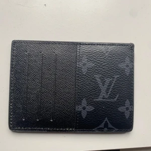 Svart kortfodral från Louis Vuitton - Säljer ett stilrent svart kortfodral från Louis Vuitton med det ikoniska monogrammönstret. Fodralet har flera kortfack och är perfekt för att hålla dina kort organiserade. Kommer i originalförpackning. Buda Gärna!