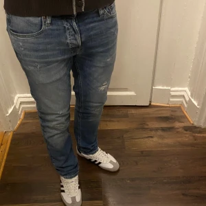 Blå jeans från Jack & Jones - Snygga blå jeans från Jack & Jones med slitna detaljer och en bekväm passform. De har en klassisk femficksdesign och en knappgylf. tveka inte att kontakta vid eventuella frågor 😀