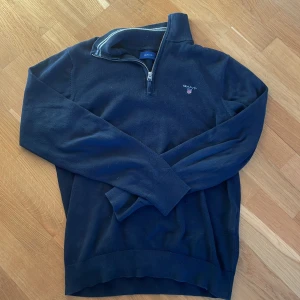 Mörkblå tröja med dragkedja från Gant - Säljer en stilren mörkblå tröja från Gant med halv dragkedja och broderad logga på bröstet. Tröjan har långa ärmar och ribbade kanter. Perfekt för en avslappnad och snygg look.      Nypris:1200kr