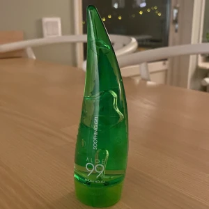Aloe 99% Soothing Gel från Holika Holika - Säljer en Aloe 99% Soothing Gel från Holika Holika. Den kommer i en grön, bladformad flaska som är både snygg och praktisk. Perfekt för att lugna och återfukta huden med naturlig aloe vera.