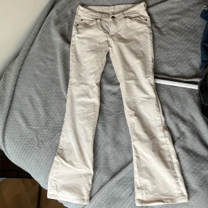 Vita manchesterbyxor - Snygga vita lågmidjade bootcut manchesterbyxor med fem fickor. Byxorna har en dragkedja och knapp framtill. Perfekta för vår och sommar. Grenhöjd 17 cm, midjemått 37cm