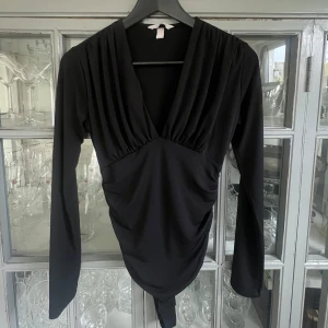 Svart långärmad blus - En perfekt middags/fest topp som går att styla till allt! Den har en draperad design framtill som ger en smickrande passform.