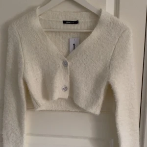 Offwhite knitted cardigan från Gina Tricot - Säljer en supermjuk och fluffig offwhite knitted cardigan från Gina Tricot i storlek XS😻har tyvär aldrig hittat nån användning för den men den är super skön och är inte alls stickig i matriallet💕 lappen sitter fortfarande kvar💖