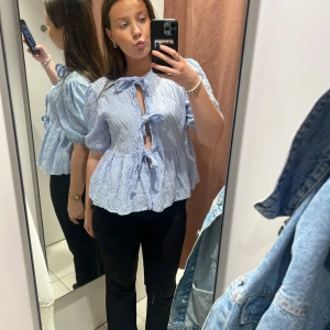 Blå randig blus med knyt - Säljer en söt blå randig blus med knyt framtill. Blusen har korta ärmar och en luftig passform som ger en avslappnad look. Perfekt för varmare dagar eller som en stilren detalj i garderoben. 💙