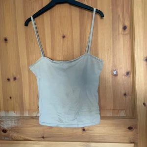 Beige linnetopp från H&M - Säljer en stilren beige linnetopp från H&M med smala axelband. Perfekt för varma dagar eller som ett basplagg i garderoben. Enkel och mångsidig design.