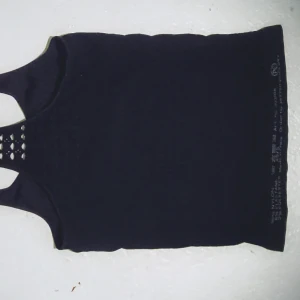 Svart super skön tränings  topp med spetsdetaljer - Svart träningstopp med spetsdetaljer på ryggen och på sidorna. Den är super behaglig att bära och man blir aldrig svettig för att den andas så bra och kommer kännas sval och skön hela dagen dessutom super duper stretchig. Verkligen ett bra linne att införskaffa sig till sommaren. Toppen har en enkel design med en twist av elegans tack vare spetsen.