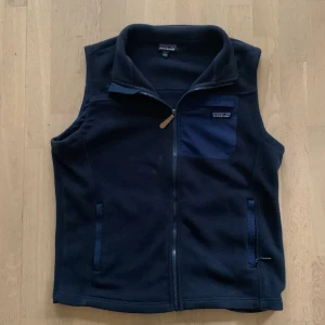 Mörkblå fleeceväst från Patagonia - Säljer en mörkblå fleeceväst från Patagonia med dragkedja och en praktisk bröstficka. Har knappast andvänt västen och den är 10/10 i skick Den är både stilren och funktionell. Orginal pris: 1350 kr. Riktigt bra pris men kan diskuteras!🙌