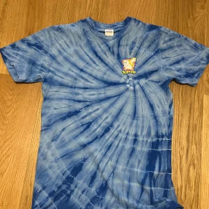 Blå tie-dye t-shirt från Ripndip - Cool blå tie-dye t-shirt från Ripndip med en stor grafisk design av en katt på baksidan och en mindre logga på framsidan. Perfekt för en avslappnad stil med en unik touch.