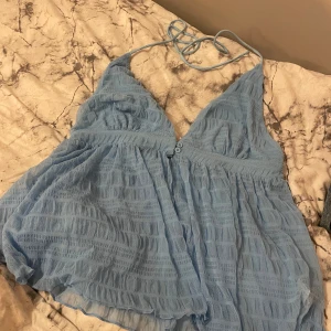 Ljusblå ärmlös topp - Säljer en luftig ljusblå topp med smala axelband och v-ringning. Aldrig använd