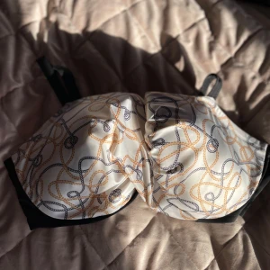 Mönstrad bikini topp med svarta detaljer - Säljer en snygg bikini bh med ett unikt mönster i beige och svart. Den har svarta detaljer och justerbara axelband för bästa passform. Perfekt för dig som vill ha något bekvämt och stilrent. 🖤storlek 95 F! Bra support, perfekt för sommaren ☀️ 