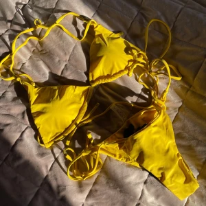 Gul bikini med knytband - Snygg gul bikini med knytband. Perfekt för soliga dagar på stranden. Inkluderar en matchande sarong för en komplett look. Bekvämt material som sitter bra. Aldrig använd, bara testad 