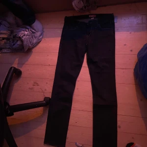 Svarta skinny jeans - Snygga svarta skinny jeans med låg midja. Perfekta för en stilren look. De har en klassisk design med dragkedja och knapp framtill.