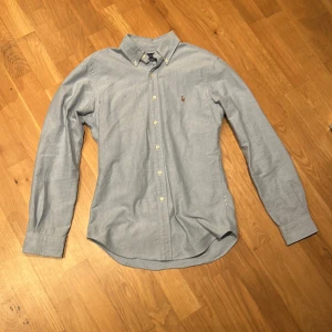 Ljusblå skjorta Ralph Lauren skjorta - Snygg ljusblå skjorta från Ralph Lauren. Skjortan är lite för liten för mig som är 183 cm. Perfekt för en stilren look. Slimfit! Ny pris ligger på 1699kr